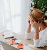 exhausted woman sitting at desk scattered with late bookkeeping records