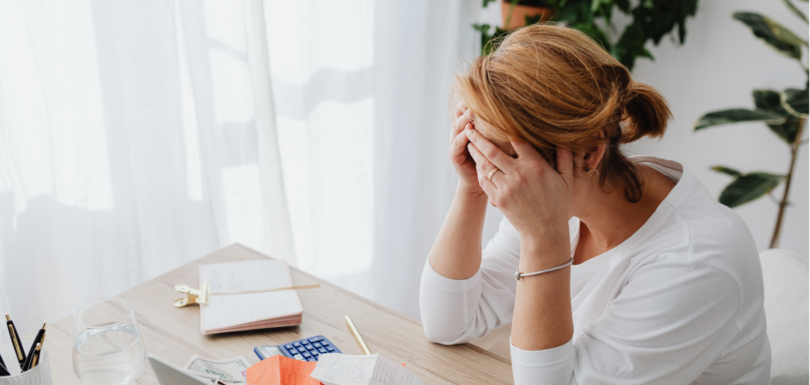 exhausted woman sitting at desk scattered with late bookkeeping records