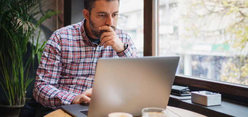 Business owner sitting at cafe working on their laptop