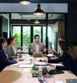 Advisor discussing S-corp tax planning with business owners around a conference table with financial reports and calculators.